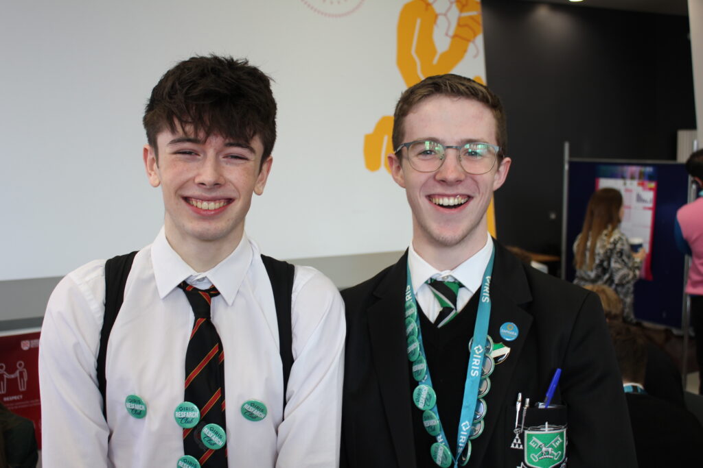Two boys smiling at camera, wearing IRIS Buttons at Greener Fragrances event in November 2023